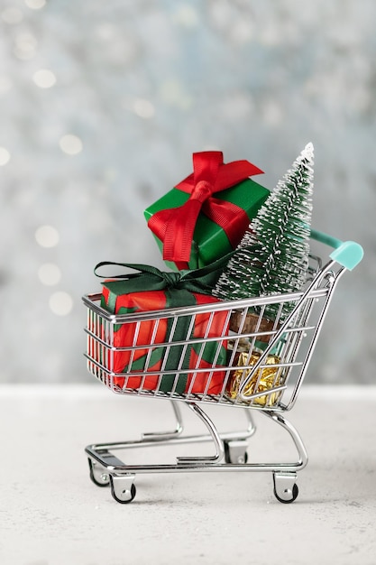 Shopping cart with Christmas presents and Christmas tree. Christmas and New year shopping concept