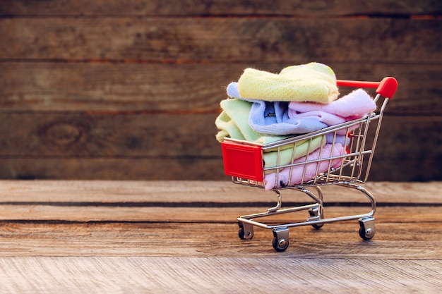 Shopping cart with clothing on the old wood background. Toned image. 