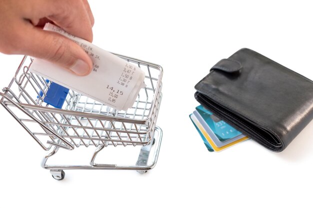 Shopping cart with credit cards and bills on white background