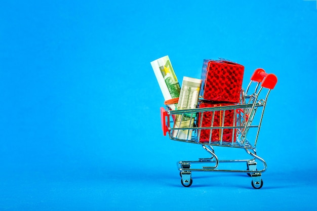 Shopping cart with money and boxes with gifts. Internet trade.