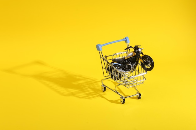 Shopping cart with a motorcycle model on a yellow background Discount and sale concept