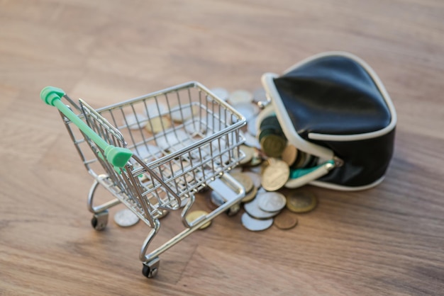 Shopping cart with wallet and coins on the wooden table