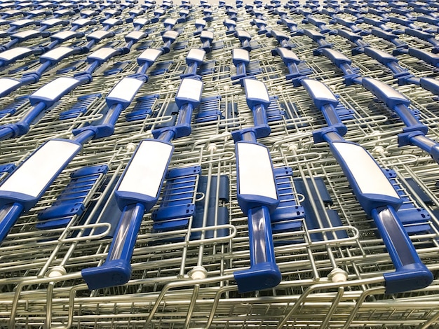 Shopping carts with blue handles are parked in front of supermarket