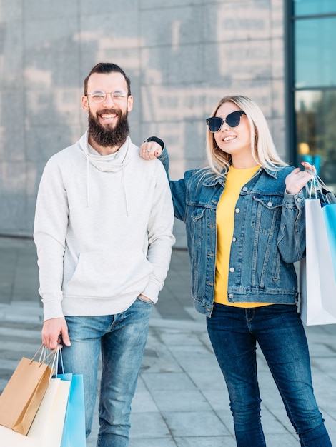 Shopping couple Urban consumerism Smiling young man and woman with paper bags in city center