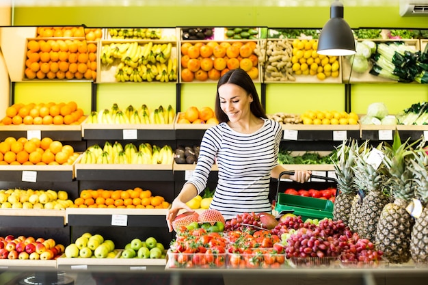 Shopping list Smiling beautiful woman stands with phone near products in store