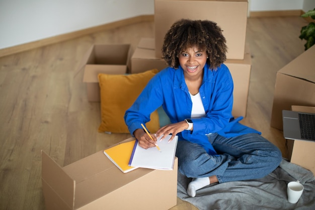 Photo shopping planning happy black woman making checklist after moving new home