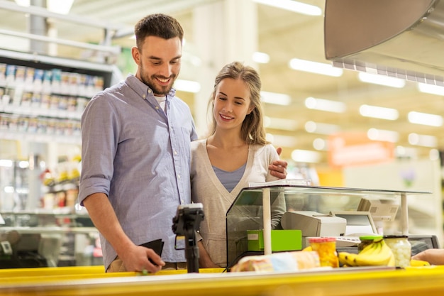 shopping, sale, consumerism and people concept - happy couple buying food at grocery store or supermarket cash register