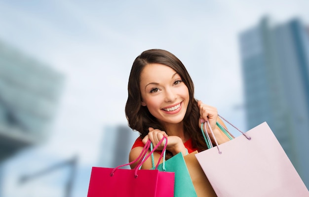 shopping, sale, gifts, christmas, x-mas concept - smiling woman in red dress with shopping bags