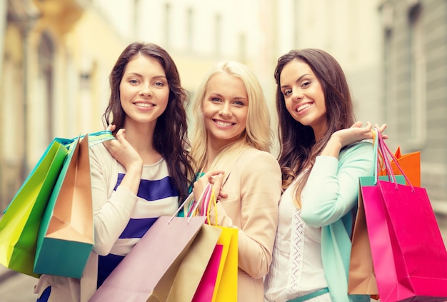 shopping, sale, happy people and tourism concept - beautiful girls with shopping bags in ctiy