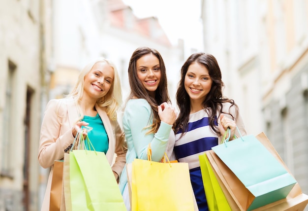 shopping and tourism concept - beautiful girls with shopping bags in ctiy