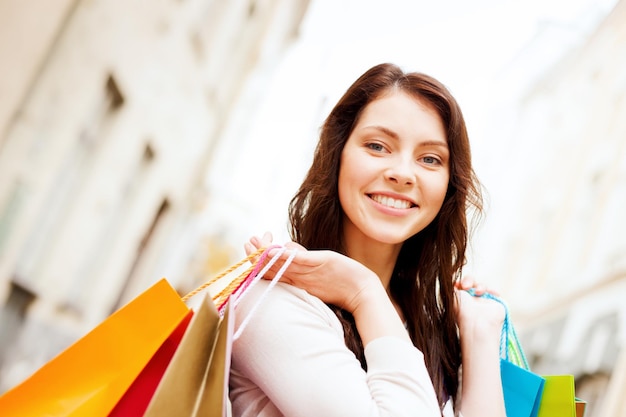 shopping and tourism concept - beautiful woman with shopping bags in ctiy