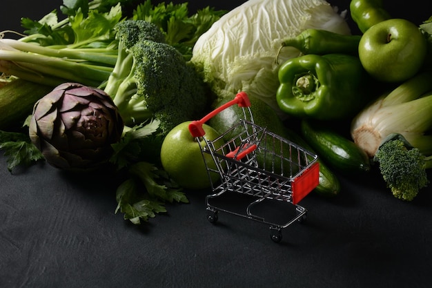 Shopping trolley cart and different fresh fruits and vegetables for layout Assortment of fresh fruits and vegetables Healthy food background Shopping food in supermarket