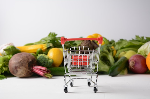 Shopping trolley cart and different fresh fruits and vegetables for layout Assortment of fresh fruits and vegetables Healthy food background Shopping food in supermarket