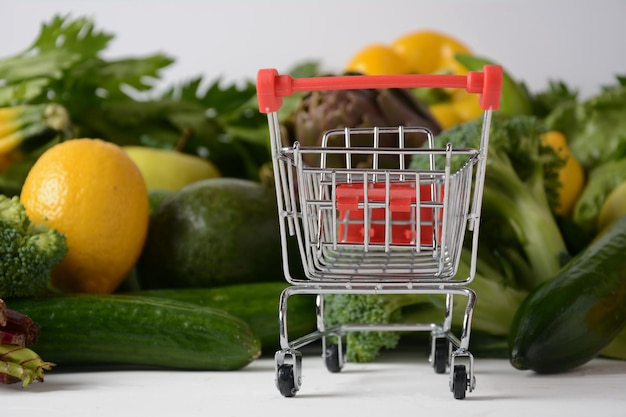 Shopping trolley cart and different fresh fruits and vegetables for layout Assortment of fresh fruits and vegetables Healthy food background Shopping food in supermarket