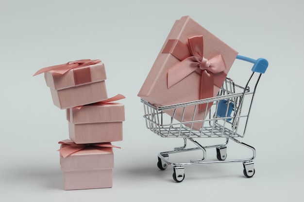 Shopping trolley and gift boxes with bows on white background. Composition for christmas, birthday or wedding.