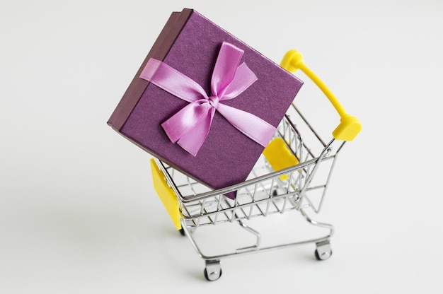 Shopping trolley toy with a gift box on white background