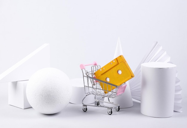 Shopping trolley with audio cassette and geometric shapes on white background Minimalism Abstract background concept art