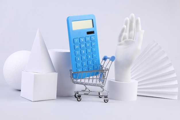 Shopping trolley with calculator and geometric shapes on a white background Concept art