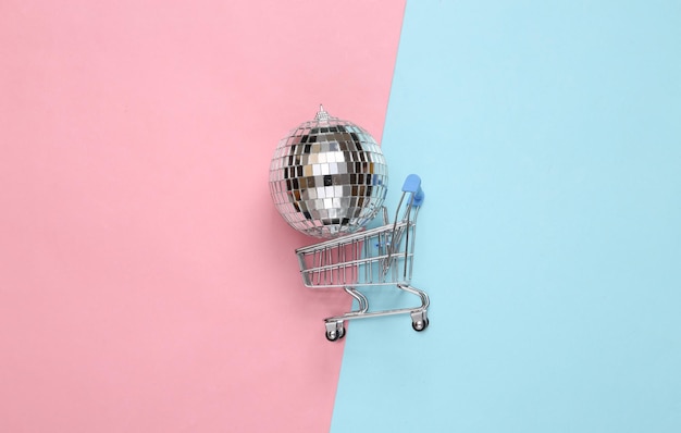 Shopping trolley with Disco ball on blue pink background Minimalism party concept