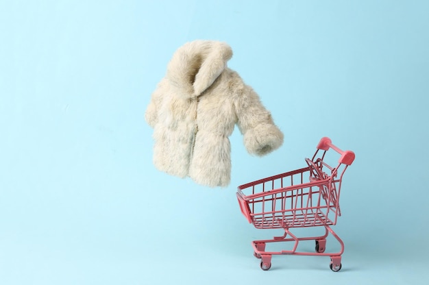 Shopping trolley with Fur coat on blue pastel background Minimalism fashion layout Concept art