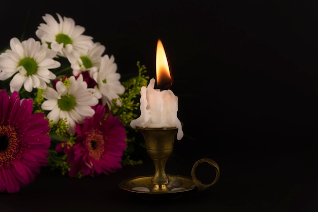 Short candle burning in closeup among flowers