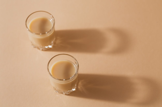 Short glasses of Irish cream Liquor or Coffee Liqueur on a light beige background