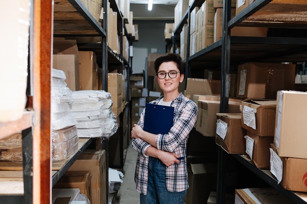 Short haired female warehouse distribution worker hugging a clipboard