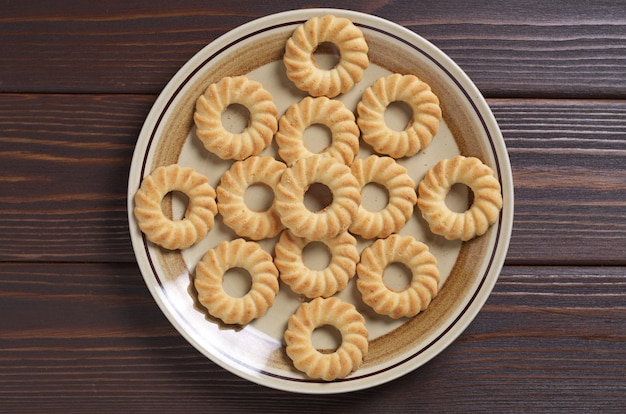 Shortbread cookies in plate on wooden background, top view