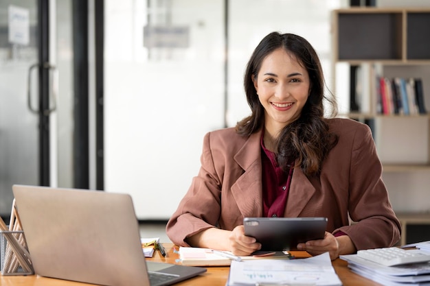 Shot of an attractive businesswoman sitting at her desk in an office Working on digiral tablet and laptop computer