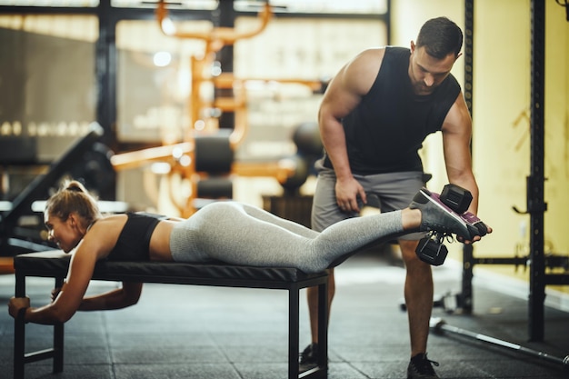 Shot of an attractive young woman working out with personal trainer at the gym.