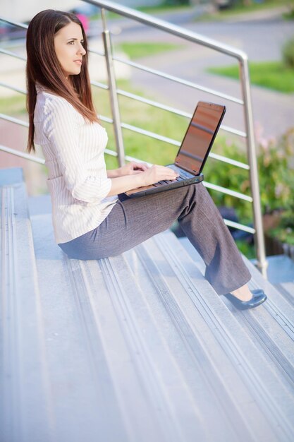 A shot of a beautiful businesswoman working on her laptop outdoor