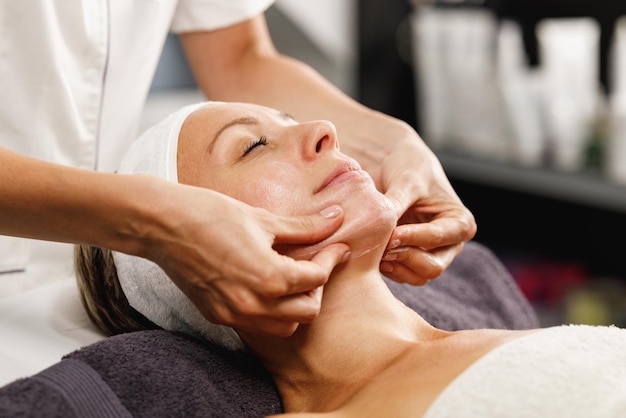 Shot of a beautiful mature woman enjoying face massage at the beauty salon.