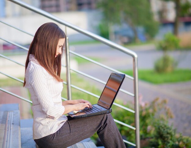 A shot of business woman working on her laptop outdoor