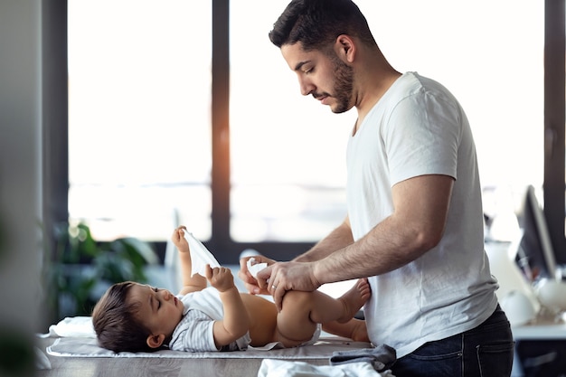 Shot of concentrated young father changing the nappy to his little baby at home.