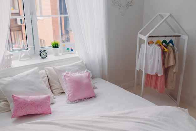 Shot of empty bedroom with no people pink pillows big window alarm clock and handmade picture Cozy interior