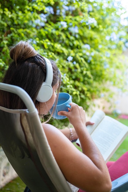 Photo shot from behind of a girl sitting in her garden drinking coffee