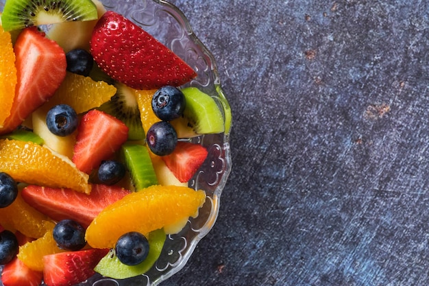 Shot from above of a transparent bowl filled with pieces of healthy fresh fruit