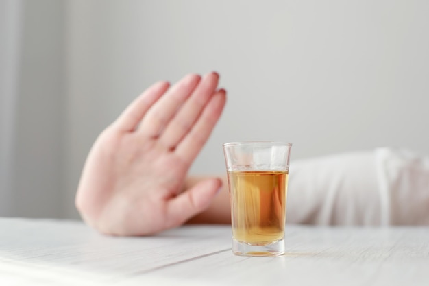 Shot glass with alcohol and hand shows no alcoholic depression