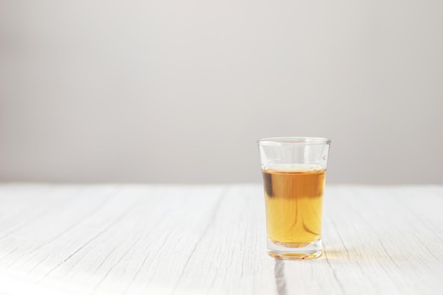 Shot glass with alcohol on a wooden table alcoholism