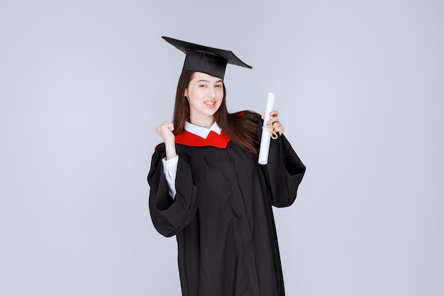 Shot of graduate student in gown with college certificate posing. High quality photo