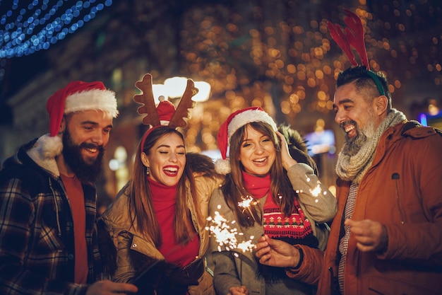 Shot of a group of cheerful young friends having fun with sparklers together outside in the evening.