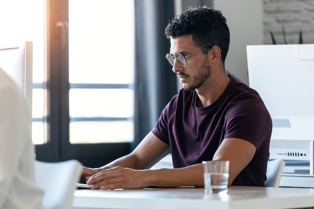 Shot of handsome young entrepreneur working with the computer in the office.