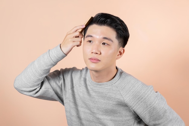 Shot of a handsome young man combing his hair