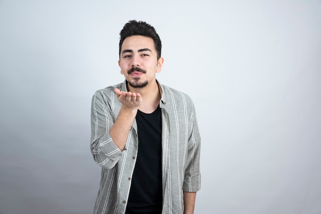 Shot of handsome young man with beard blowing a kiss.