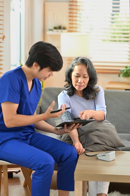 Shot of health visitor giving recommendations and measuring blood pressure middle age woman patient during home visit