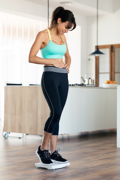 Shot of healthy young woman, happy to see that she has lost weight on scale weight at home.