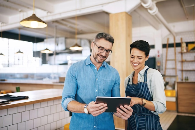 Shot of a man and woman using a digital tablet together in their coffee shop