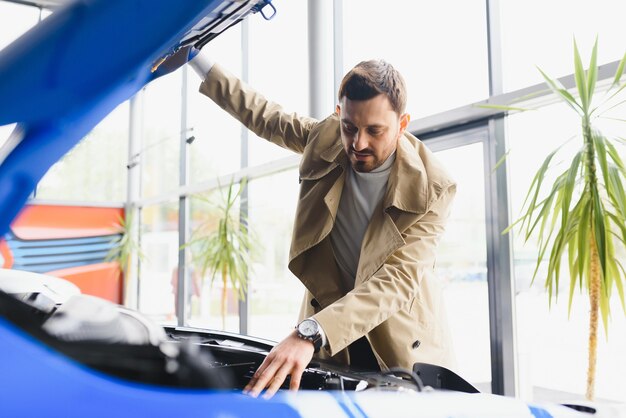 Shot of a mature man examining engine of a new automobile at the car dealership looking under the hood copyspace mechanics modern technology driving vehicle horsepower motor automotive.