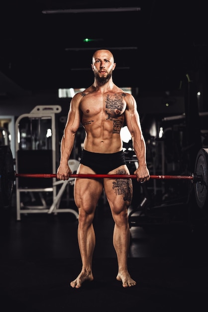 Shot of a muscular bodybuilder doing hard training with barbell at the gym.