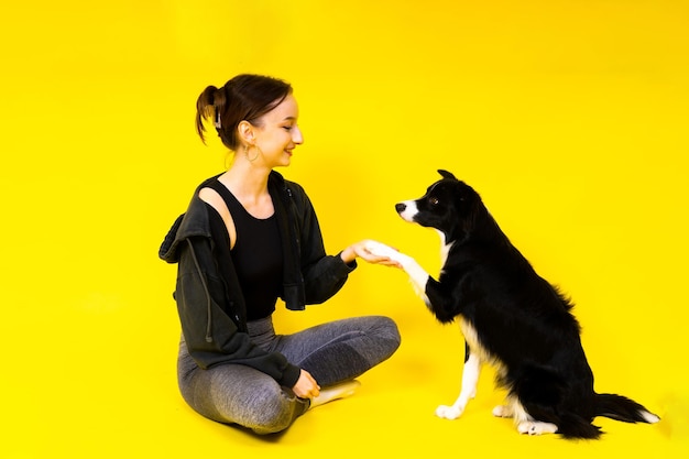 Shot of a sport female in leggings with a border collie dog isolated on yellow and red background